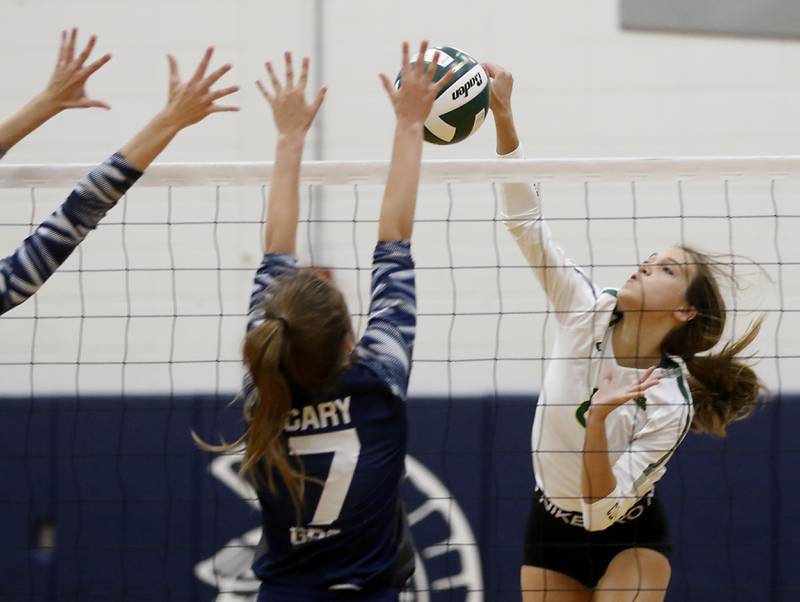 Crystal Lake South’s Bella Toniolo, right, hits the ball as Cary-Grove’s Addison DeKett, left, tries to block the ball during a Fox Valley Conference volleyball match Thursday, Aug. 25, 2022, between Cary-Grove and Crystal Lake South at Cary-Grove High School.
