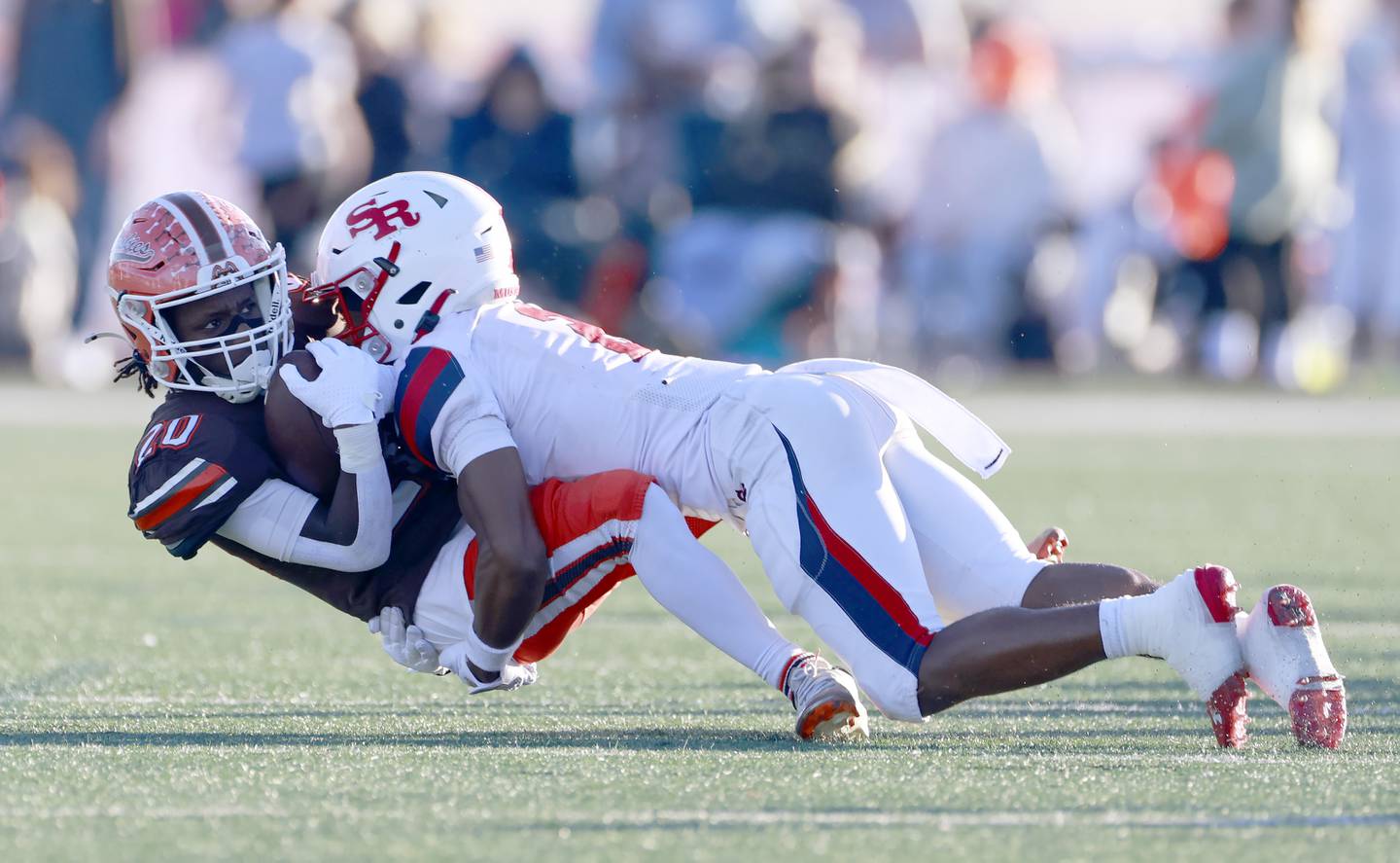 Hersey's Zel Walton (20) is wrapped up by St. Rita's James Franklin Iii (2) during the IHSA Class 6A Football Quarterfinal Saturday, Nov. 15, 2025 in Arlington Heights.