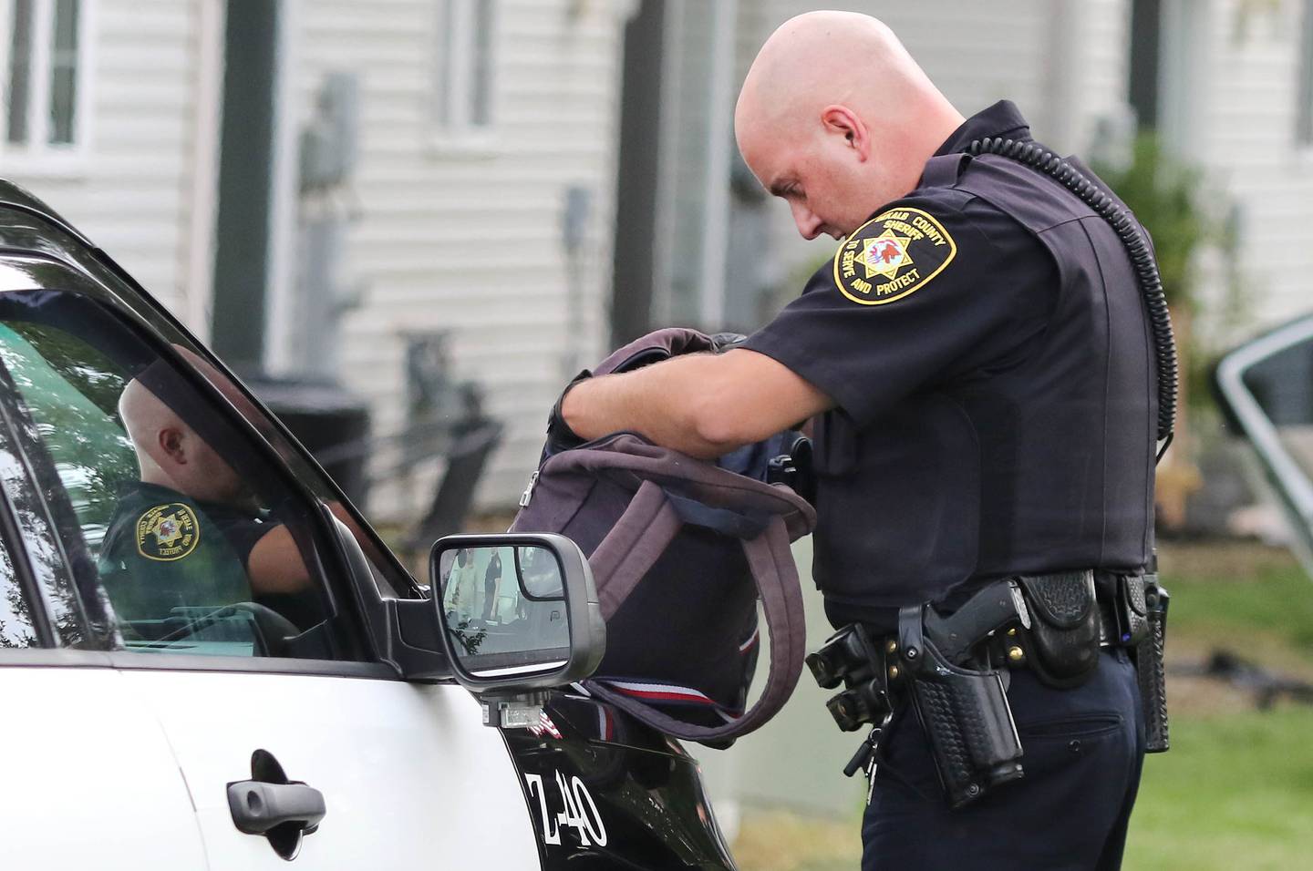 A DeKalb County Sheriff's officer searches a backpack that came out of a car in the grass behind Cambridge Square Townhomes off of Fotis Drive in DeKalb Monday, Aug. 29, 2022, after the driver led police on a chase through the area.