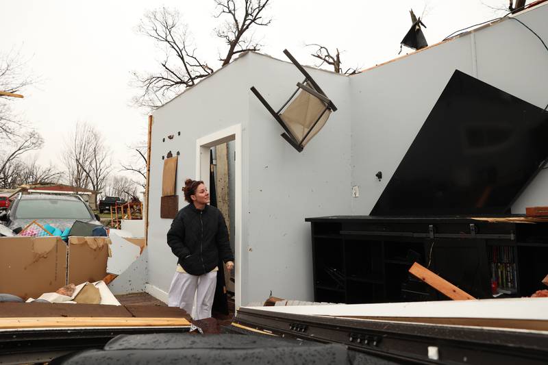 Emily LaVoie observes some damage, including a patio chair lodged in the wall, at her home along Elmwood Drive in Aroma Township on Wednesday, March 11, 2026, following the March 10 tornado in Kankakee County.