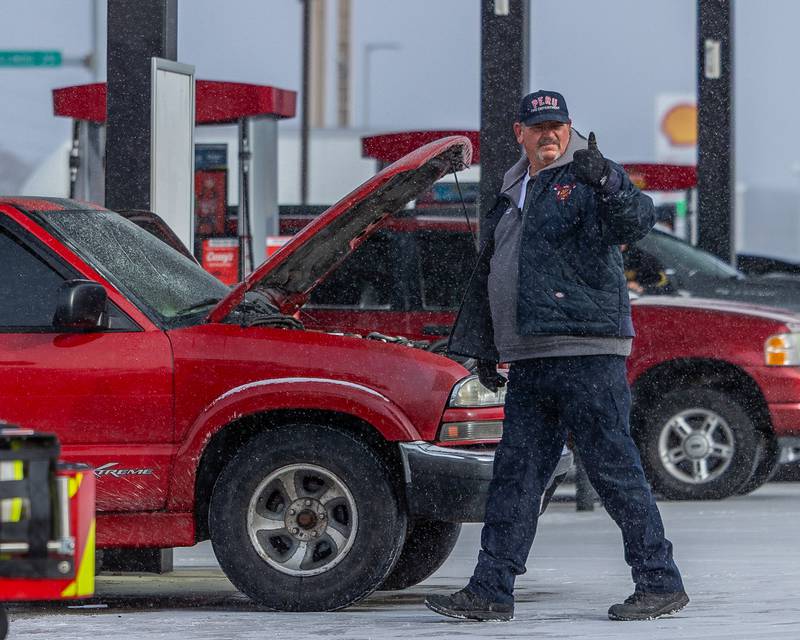 Peru Firefighter gives 'thumbs up' to pedestrian at scene of internal electrical fire of vehicle near gas pump on Tuesday, December 30, 2025 at Casey's on 1100 Shooting Park Road in Peru. The fire was extinguished by 15 year old driver Jesus Gonzalez of Streator.