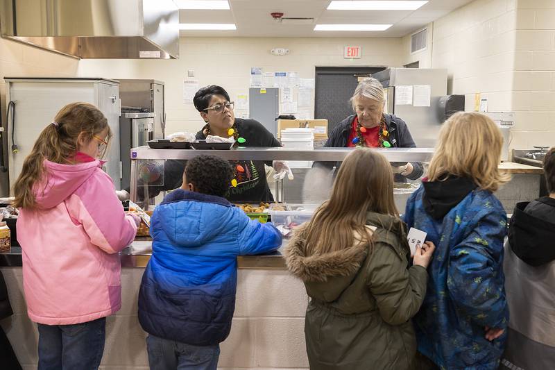 Jefferson School lunch servers Priscilla Smith (left) and Sheila Brady dish up the goods Tuesday, Dec. 17, 2024, in Dixon. Destiny McElhinney of Dixon is leading a fundraiser with the goal of wiping out student lunch debt at the school.