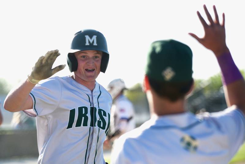 Bishop McNamara's Jacob Lotz, left, high-fives Fightin' Irish teammate Taylor Fuerst after scoring a run during McNamara's game at Kankakee Friday, May 9, 2025.