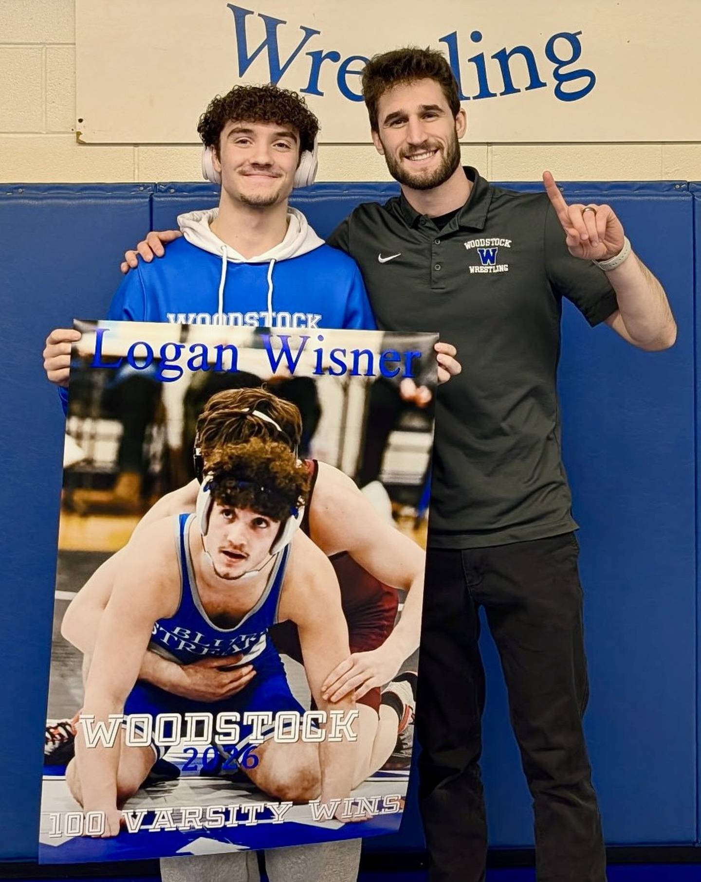 Logan Wisner (left) is presented with a poster commemorating his 100th win with the Woodstock wrestling program. Wisner is pictured with coach Matt Kitsis.