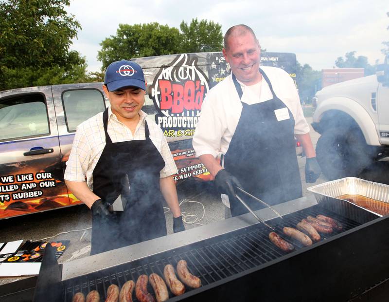 Marcos Martinez, owner of Dockers North, and Brian Bezak, owner of Mexican Paradise Cafe, stand side-by-side making brats during the final concert of the It’s Thursday” summer concert series on August 10th in Antioch. The event and its proceeds were dedicated to Huntley, a child who was injured during the Taste of Summer in July. 
Photo by Candace H. Johnson for Shaw Local News Network