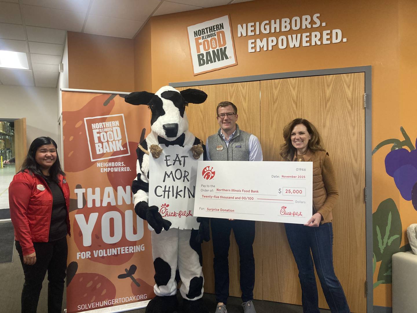 Joy Dodge (from left), Cow, and Kris Yoder present Northern Illinois Food Bank President and CEO Julie Yurko on Monday, Nov. 24, 2025.