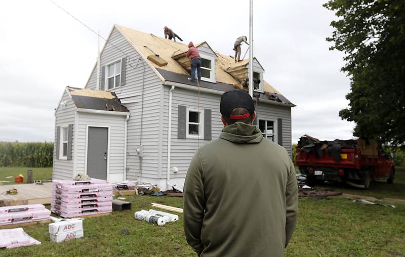 U.S. Army veteran Philip Arnold watches as a new roof is installed on his home near Harvard on Thursday, Sept. 7, 2023, through the Owens Corning Roof Deployment Project and Habitat for Humanity.