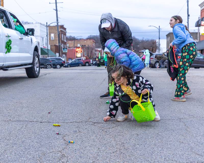 Teagan Jordan picks up candy from street at the St. Patricks Day parade on Tuesday, March 14, 2026 on Main Street in Marseilles.