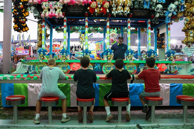 A group of kids prepare to compete in a carnival game during the Will County Fair on Aug. 21, 2025.