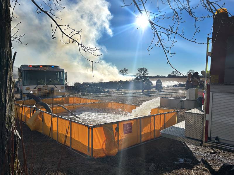 Firefighters from several departments responded to a field and hay bale fire at a farm on West Pines Road between Polo and Oregon on Monday, Feb. 23, 2026. Here, water is pumped into a portable water tank for the Polo engine to supply hoses.