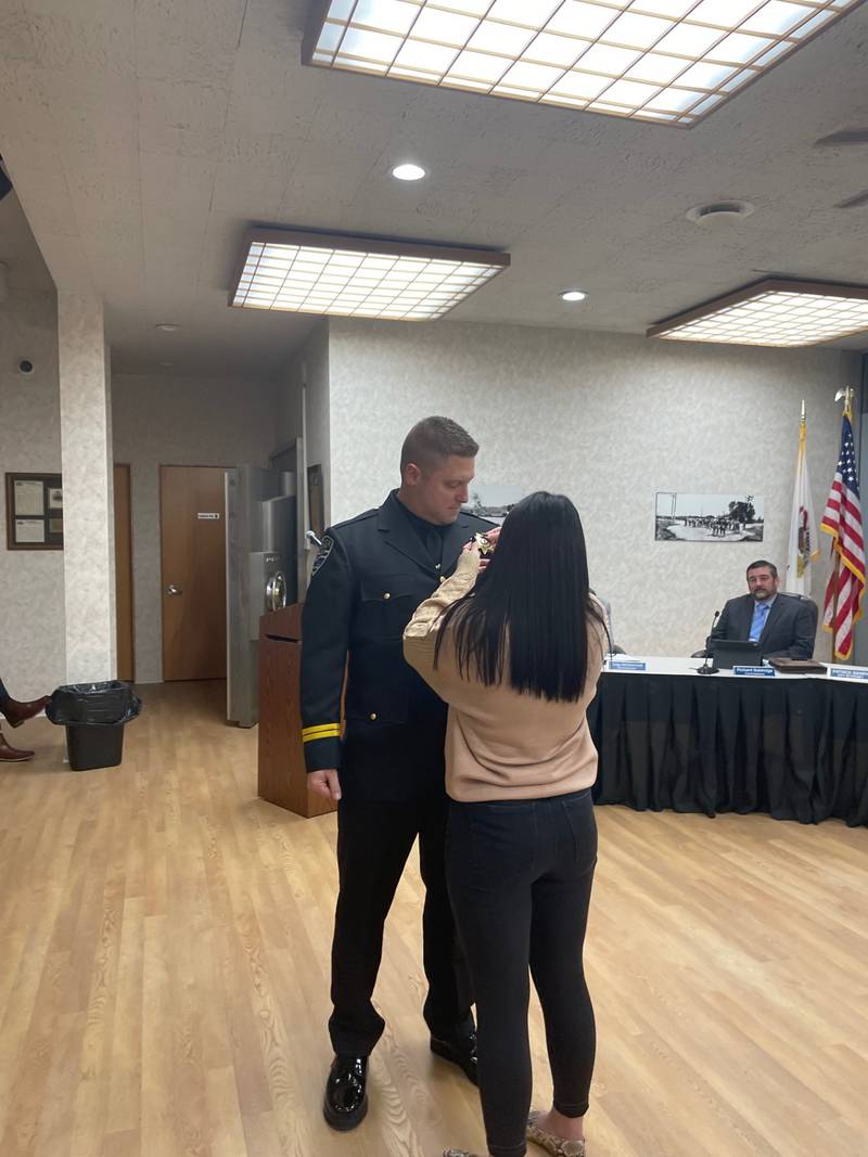 Newly-sworn Oglesby Deputy Police Chief Evan Duttlinger dons his badge Monday, Jan. 6, 2025, with help from girlfriend Ashley Bain.