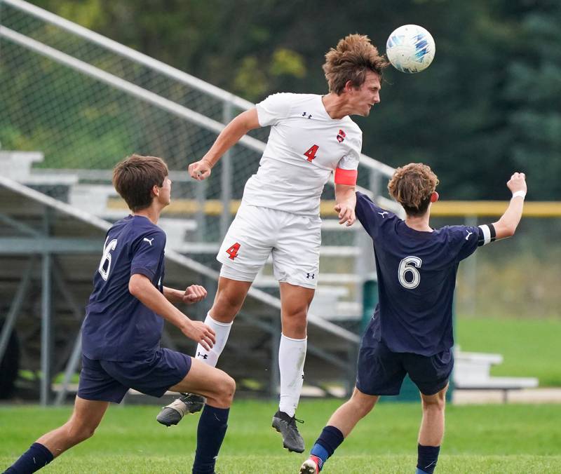 Oswego’s Ryan Walsh (4) goes up high for a header over Oswego East's Mariano Ramirez (16) and Nicholas Smith (6) during a soccer match at Oswego East High School on Tuesday, Sept. 26, 2023.