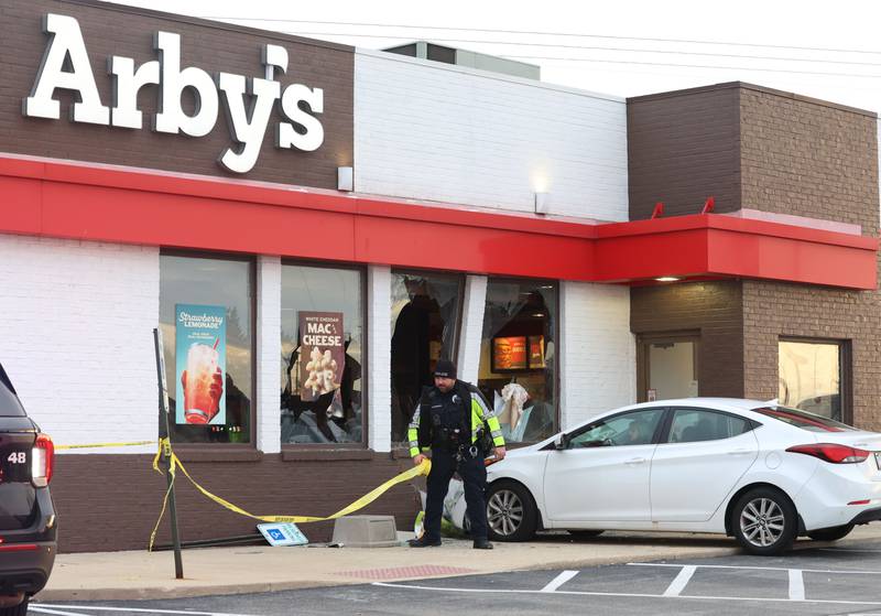 Peru Police officer Brad Anderson places caution tape around the perimeter of Arby's after a car stuck the building on Friday, Dec. 19, 2025 in Peru. The incident happened shortly after 3:30p.m. No injuries were reported.