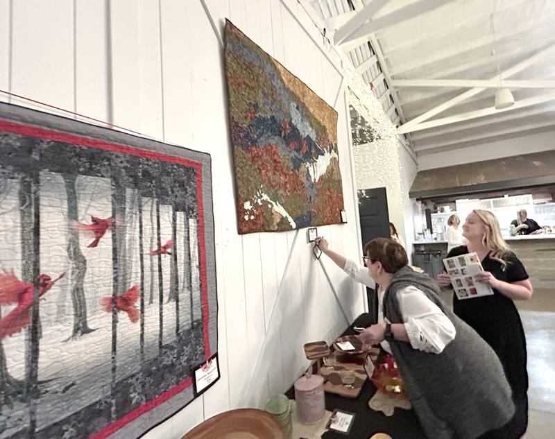 Kelsey Rogers of Rock Falls watches as a Serenity volunteer marks her choice of art during the Serenity Hospice and Home’s Fourth Annual Art Dash fundraiser on Wednesday, April 9, 2025, at River’s Edge Experience, 103 S. First St., Oregon. Rogers, a Rock Falls resident and Oregon native, chose an applique wall hanging created by Sandie Copeland.