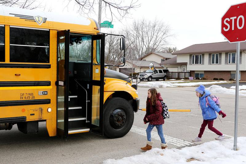 Two grade schoolers board their bus during last school year.