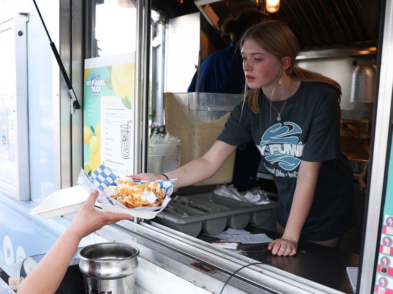 A worker hands out an order of funnel cake at the My Funnel truck at the World of Food Trucks on Saturday, May 18, 2024 at Renwick Community Park in Plainfield