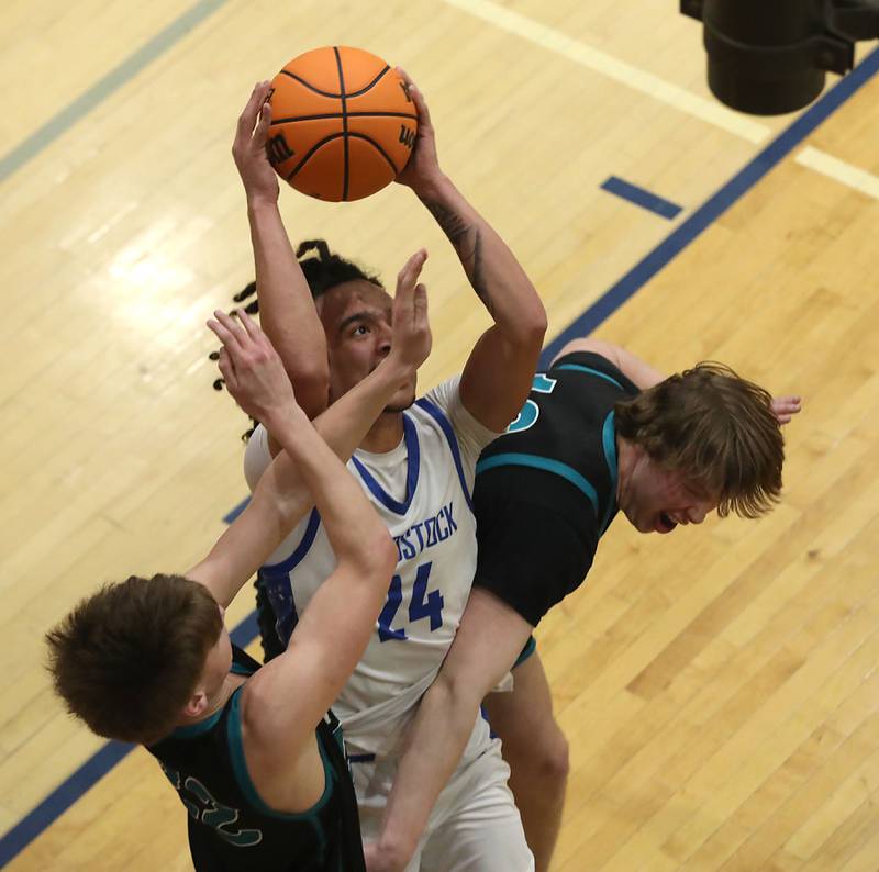 Woodstock's JJ Stokes tries to muscle up a shot between Woodstock North's Curtis Czeslawski (left) and Brady Rogers (right)during a Kishwaukee River Conference boys basketball game on Wednesday, February. 18, 2026, at Woodstock High School.