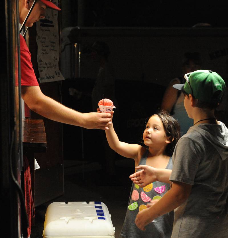 Gracelyn DeKing, 5 gladly receives her frozen treat from the Newark FAA Sno Cone stand during the Kendall County Fair in Yorkville on Saturday, August 6, 2022.