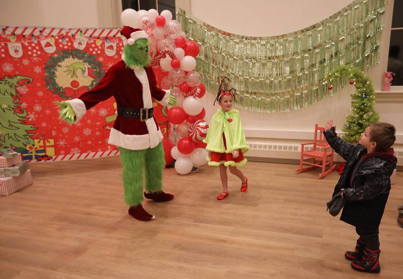 Charles Hapeman, 4, of Woodstock waves to the Grinch during the Grinch & Greet before the Lighting of the Square on Friday, Nov. 28, 2025, in Woodstock.The annual holiday season event featured brass music, caroling, free doughnuts and cider, food trucks, festive selfie stations and shopping.