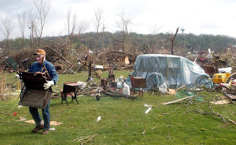 Ed Stewart carries a chair across his property during the days following the Utica Tornado in 2004
