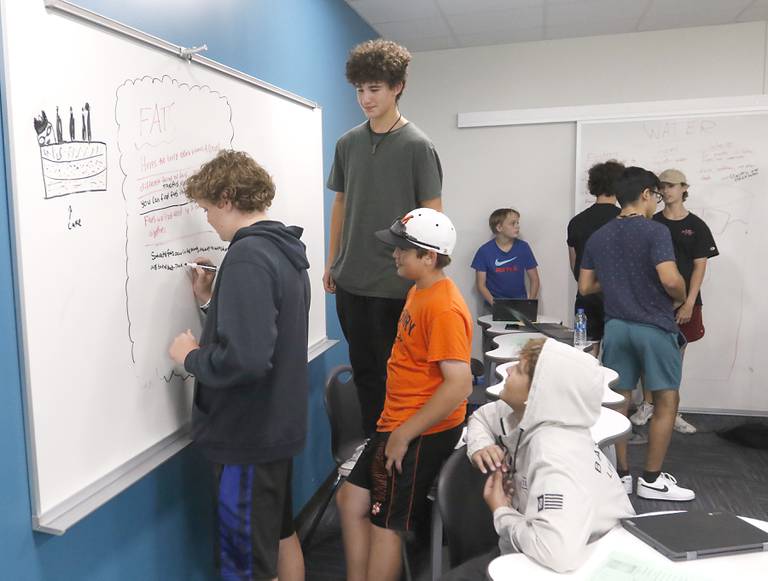 Jayden Murray writes about fat on the whiteboard as other classmates watch Monday, July 11, 2022, while they take a health "get-ahead" course during summer school at McHenry Community High School, 4716 W. Crystal Lake Road, in McHenry.