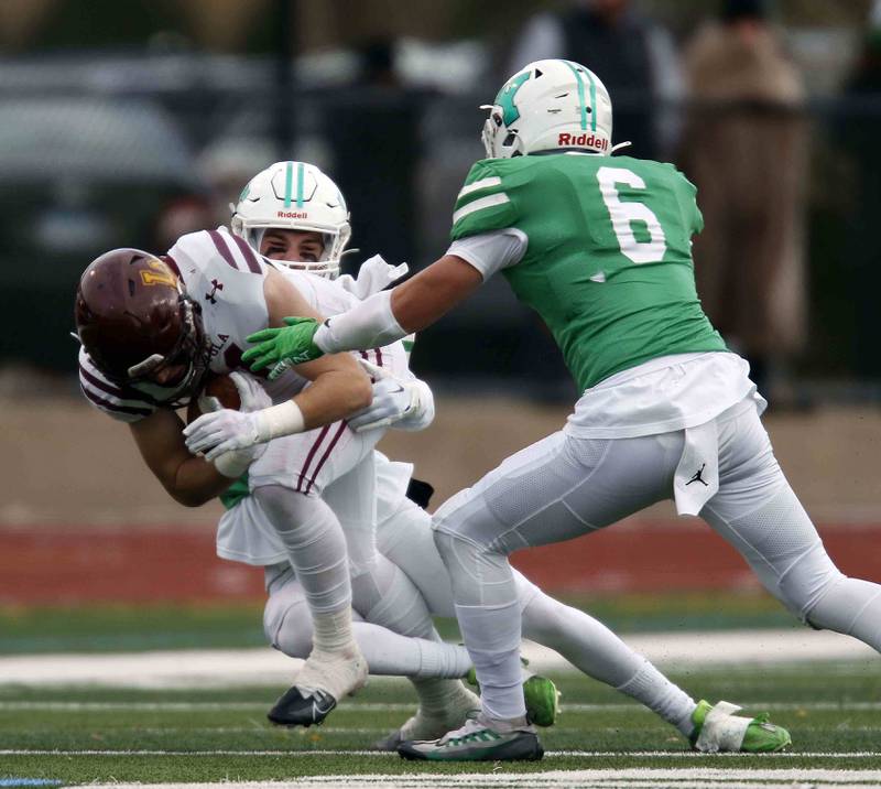 York’s Reece Richardson (29) and David Loch (6) bring down Loyola's Corey Larsen (11) during the IHSA Class 8A semifinal football game Saturday November 19, 2022 in Elmhurst.