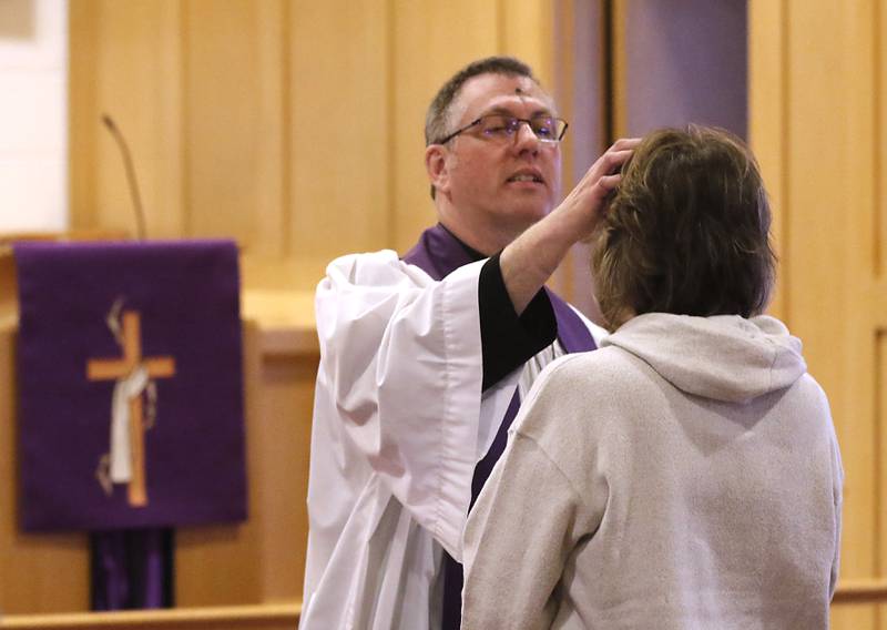 Rev. Mark Buetow, of the Zion Evangelical Lutheran Church in McHenry, places ashes on a church member on Wednesday, Feb, 14, 2024, during a service for the students and church members on Ash Wednesday.