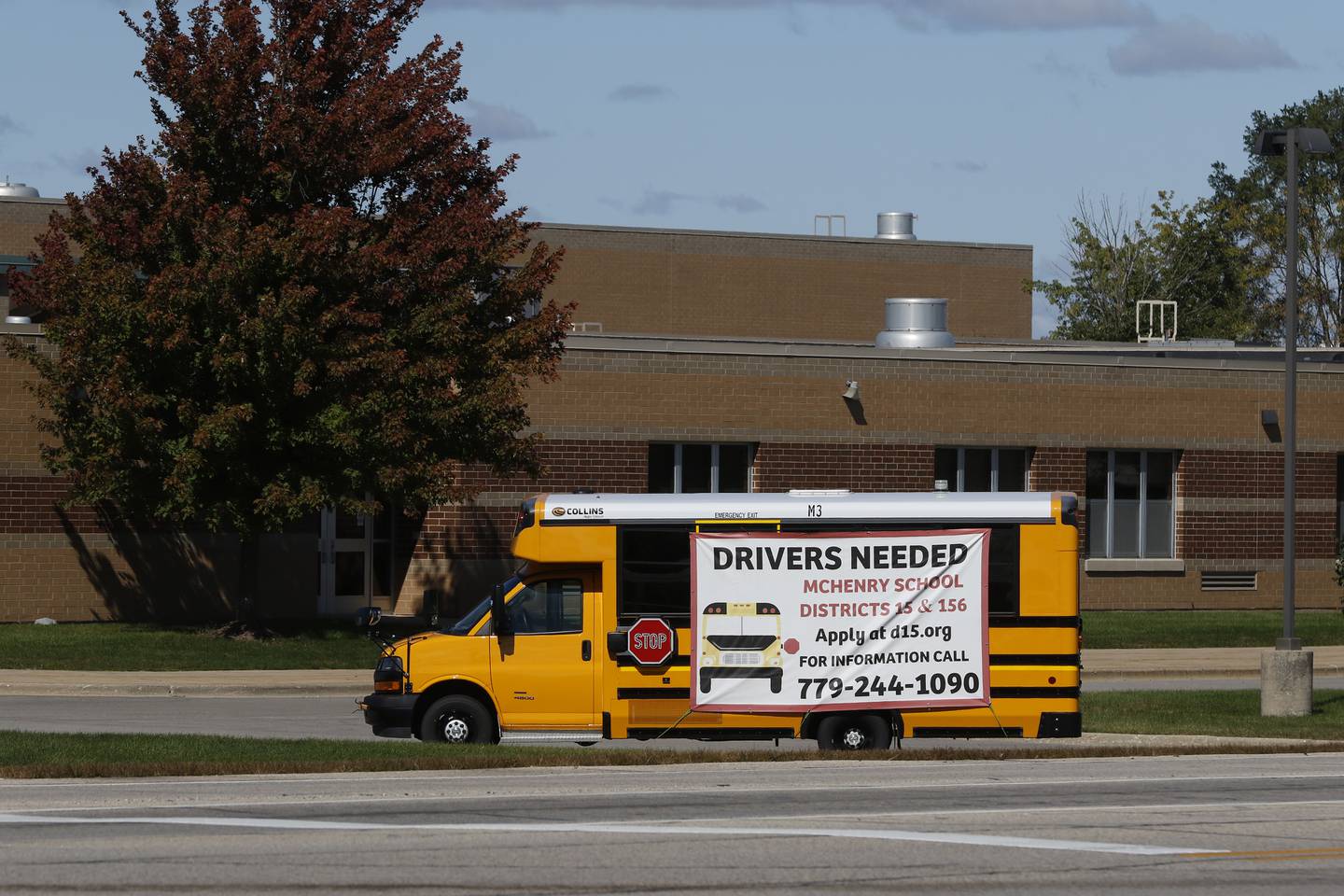 A bus with a sign advertising to hire bus drivers is parked outside McHenry Middle School on Tuesday, Sept. 27, 2022.