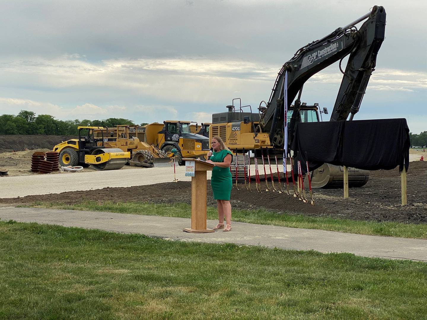 Greater Joliet Area YMCA President Katy Leclair addresses a crowd in front of bulldozers at the groundbreaking for the new Morris Hospital YMCA.