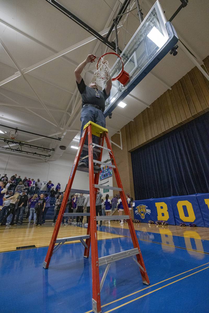 A Serena Highschool Staff member cuts down the net after the IHSA class 1A boys basketball regional championship on February 23, 2024 at Serena High School.