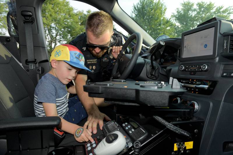 Rooney Schmidt, 4 of Geneva gets the chance to turn on the lights and siren in a Police car with the help of Geneva Police Sergant Jan Walkosz during Geneva's first National Night Out event on Tuesday, Aug 5, 2025 in Geneva.