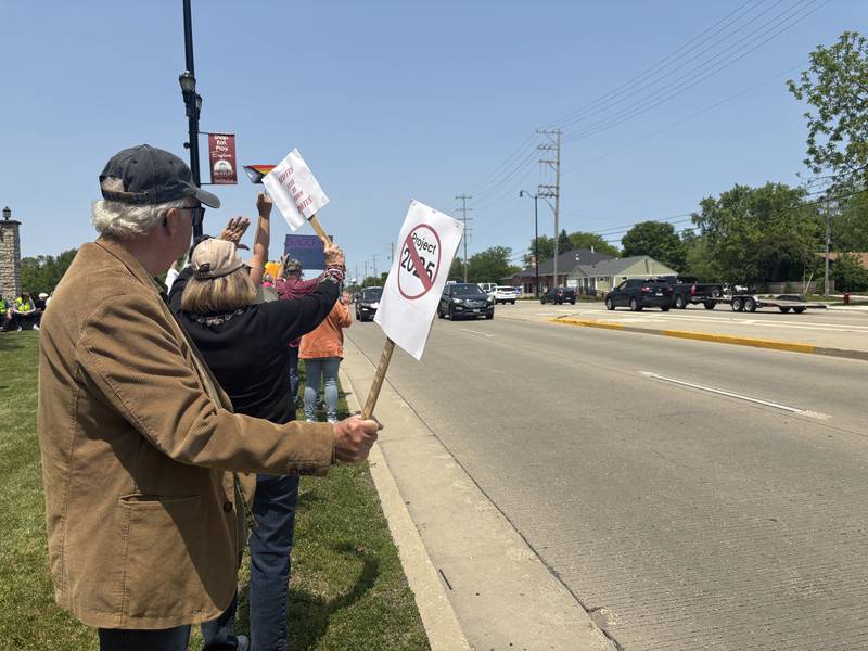 People hold up signs along Route 47 in Huntley during a rally against President Donald Trump May 31, 2025.
