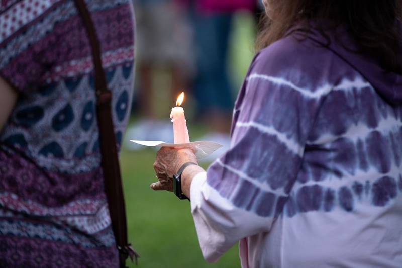 A woman holds a candle at a candlelight vigil was held at the Kane County Courthouse in Geneva on Wednesday, July 6, 2022. The vigil was organized to honor the mass shooting at a Fourth of July Parade in Highland Park.