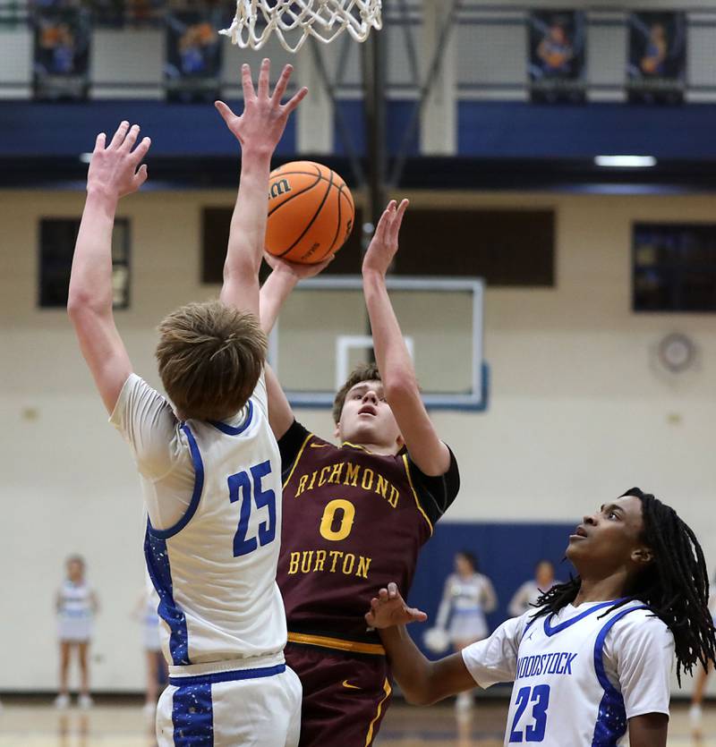 Richmond-Burton's Gavin Radmer (center) shoot the ball between Woodstock's Liam Laidig (left) and Marc Thomas (right) during a Kishwaukee River Conference boys basketball game on Wednesday, February. 4, 2026, at Woodstock High School.