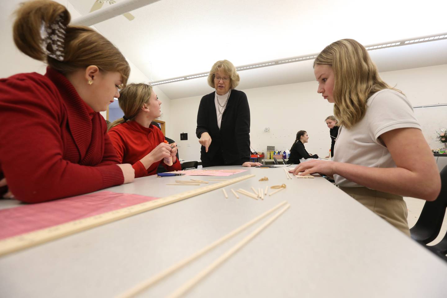 Mrs. Lynn Quick helps students Lenee McCoy, Aubrey Duttlinger, and Emma Short with building a bridge out of wood on Wednesday, March 22, 2023, at Holy Family School in Oglesby.