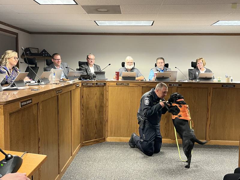 The newest recruit, 3-year-old Lab Flo, was sworn in at the Nov. 13 Antioch Village Board meeting. She is shown with Antioch Cmdr. Nick Garcia.