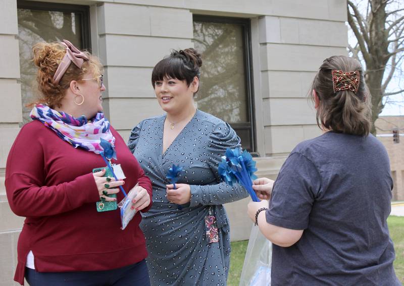 A member of Shining Star Children's Advocacy Center hands out blue pinwheels to some of the 50 people who gathered at the Old Lee County Courthouse on Friday, April 14, 2023, to observe National Child Abuse Prevention Month.