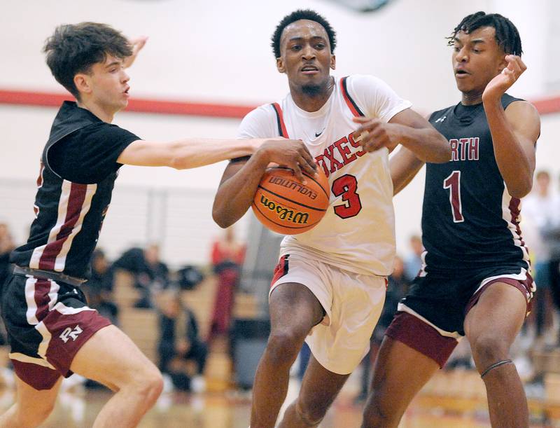 Yorkville's Dayvion Johnson (3) gets fouled driving between Plainfield North defenders Drew Jensen and Demir Ashiru (1) during a boys’ varsity game at Yorkville High School on Tuesday, Nov. 29, 2022.