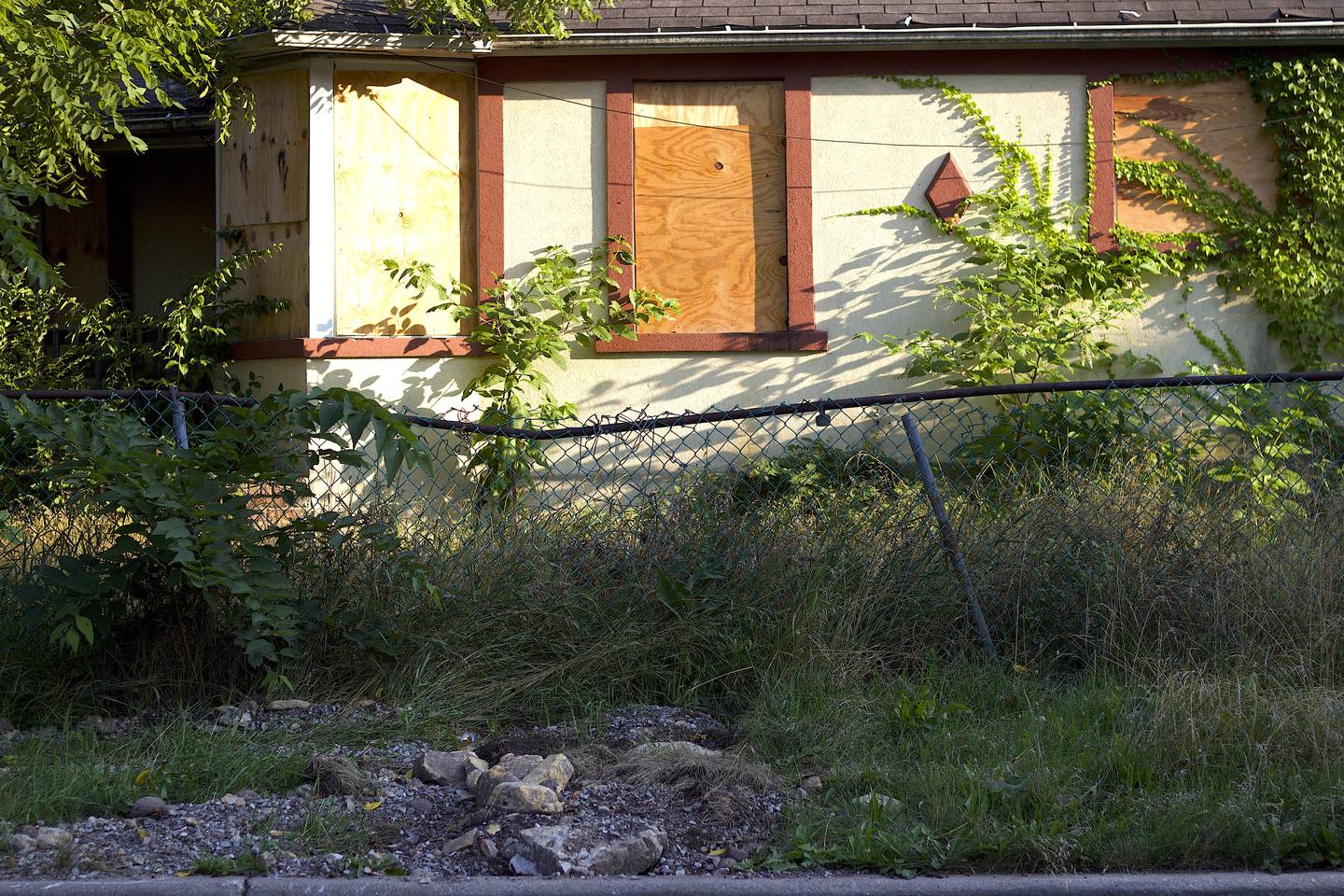 A boarded-up residence with a broken fence, tall grass and unruly foliage seen on Tuesday, July 22, 2025, on Water Street in Joliet.