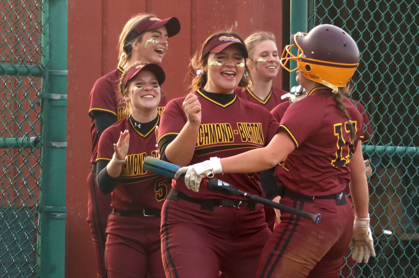 Richmond-Burton’s Sydney Hird, right, is greeted by Norah Spittler, center, and others at the dugout after scoring the go-ahead run in an extra-inning win in varsity softball at Marengo Wednesday evening.