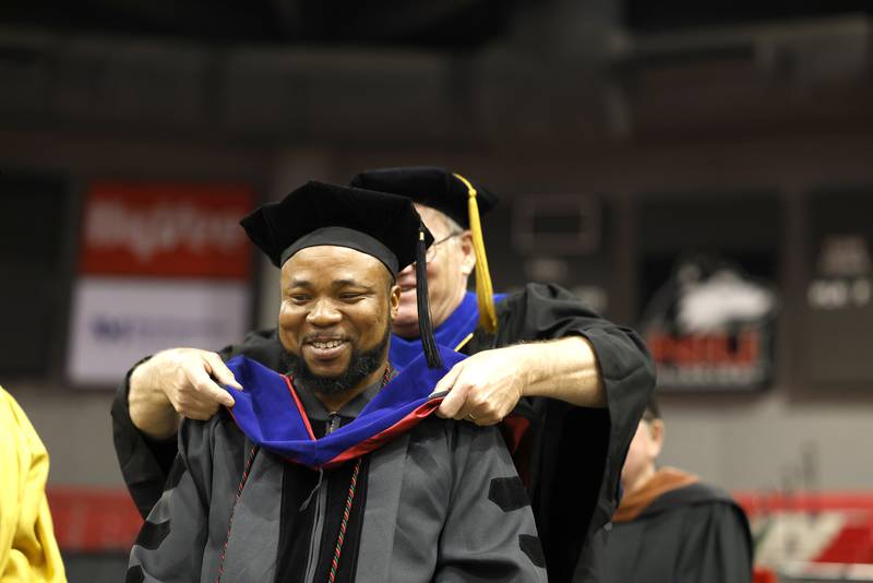 A Northern Illinois University graduate student receives his accolades during a May 12, 2023 Commencement ceremony at the NIU Convocation Center in DeKalb.