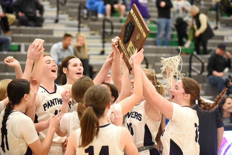 The Manteno girls basketball team celebrates with the IHSA Class 2A Seneca Regional championship plaque after defeating Wilmington 50-37 in the championship game Thursday, Feb. 19, 2026.