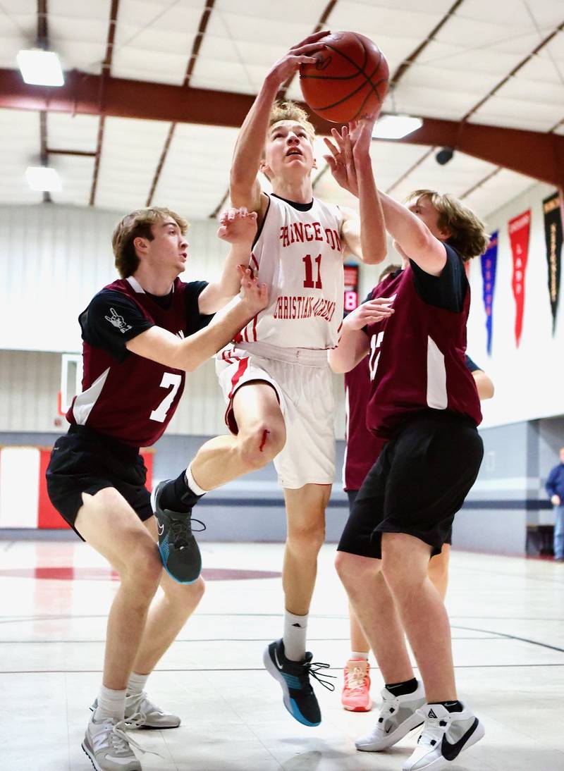 Princeton Christian Academy's Andrew Gibson drives on Ottawa Christian Academy's Brody Pagakis (left) and Jackson Poggi (17) Tuesday at Howard Hoffman Memorial Gym. The Eagles won 57-42.