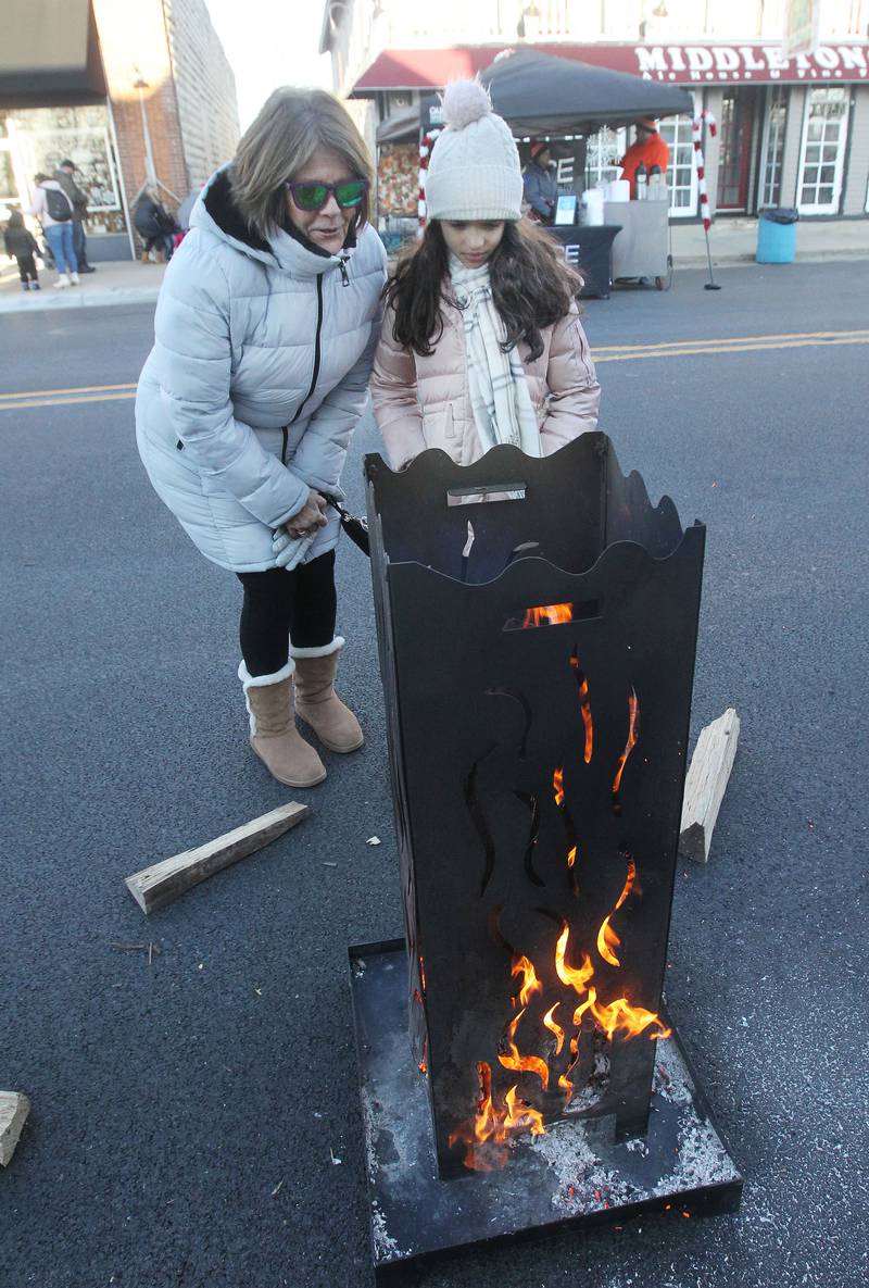 Pat Rust, of Wauconda and her granddaughter, Olivia Lomanto, 7, of Arlington Heights keep warm next to the fire pit during the Holiday Walk on Main in Wauconda. The event was sponsored by the Wauconda Area Chamber of Commerce.