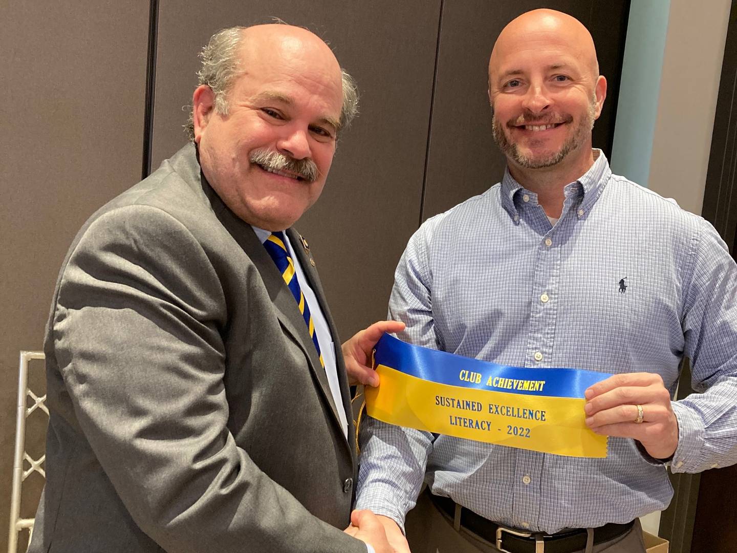 Andy Axup, left, a professor at St. Ambrose University and the literacy committee chairman for Rotary District 6420, presents Tom Myers, president of the Rock Falls Rotary, with two awards. Both awards recognize the Rotary club's effort to improve literacy in the community.