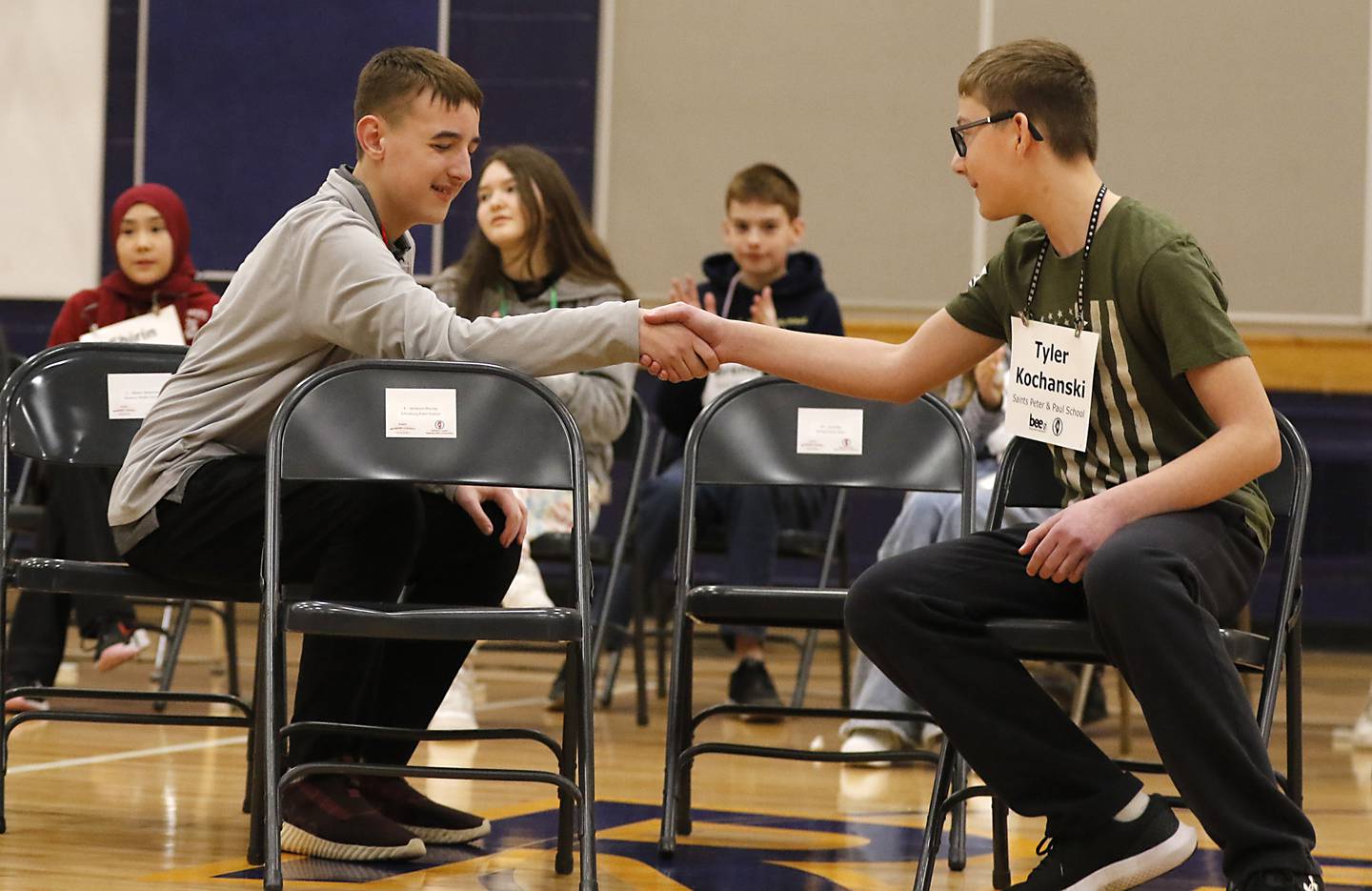 Keegan Schultz (left), a student at Marengo  Community Middle School, shakes hands with Tyler Kochanski from Saints Peter and Paul Catholic School after Kochanski won the McHenry County Regional Office of Education’s 2025 Spelling Bee on Wednesday, March 19, 2025, at Bernotas Middle School in Crystal Lake.