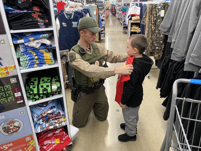 Officer Jacob Wessels with the Illinois Conservation Police helps Dylan size up a new t-shirt.