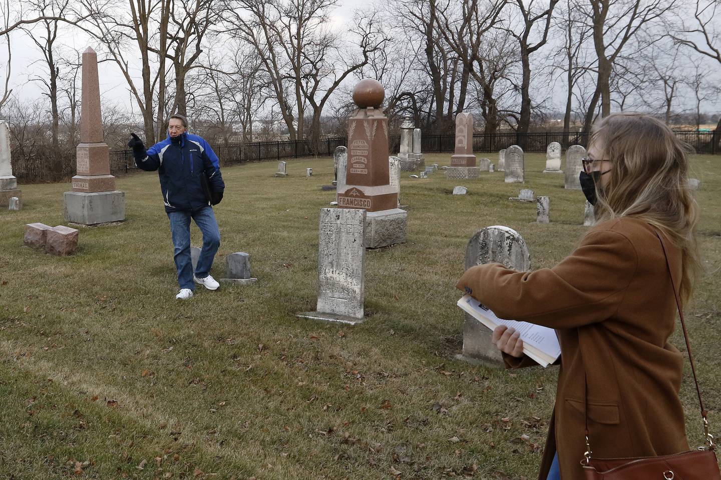 Amanda Helma and Doug Peterson, both of the McHenry area, search through Ostend Cemetery to find an unmarked burial plot on Tuesday, Dec. 21, 2021, in McHenry.  The two are working to identify the boy who died in 1963 and issue a headstone for him.