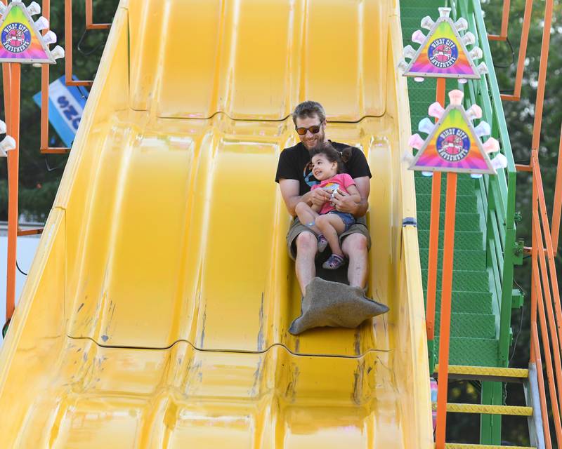 Michael Kraus goes down the slide with his daughter, Frankie, 3 years old, of Big Rock during the Friday June 17, 2022 portion of PrairieFest held in Oswego.