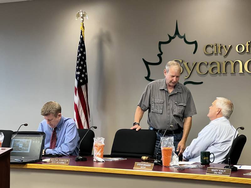 Sycamore City Manager Michael Hall looks over his notes as 1st Ward Alderman Alan Bauer and Mayor talk ahead of a Sycamore City Council meeting on Aug. 5, 2024.